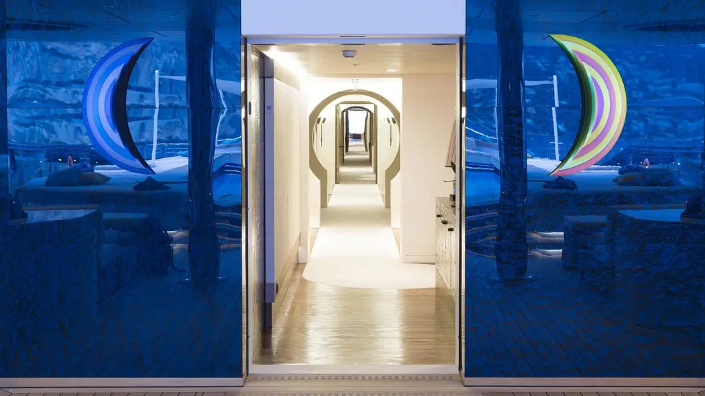 A corridor seen through an open doorway, with a series of arched openings along its length, between two dark blue panels