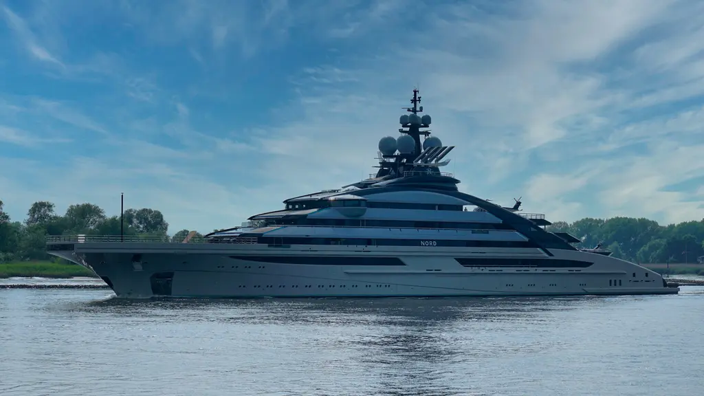 Nord in starboard profile on a river, trees along the bank behind her