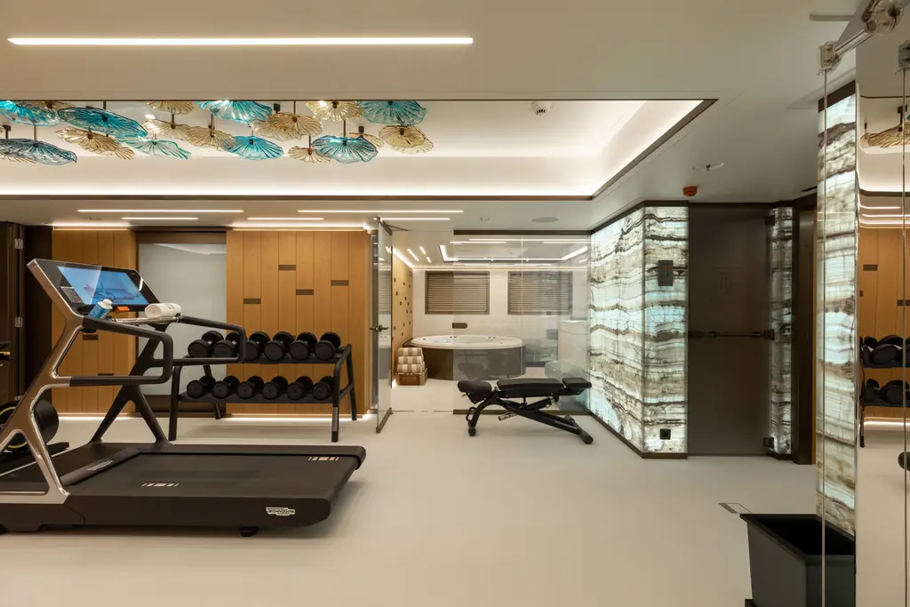 Gym with a treadmill, weights rack and backlit onyx wall panels