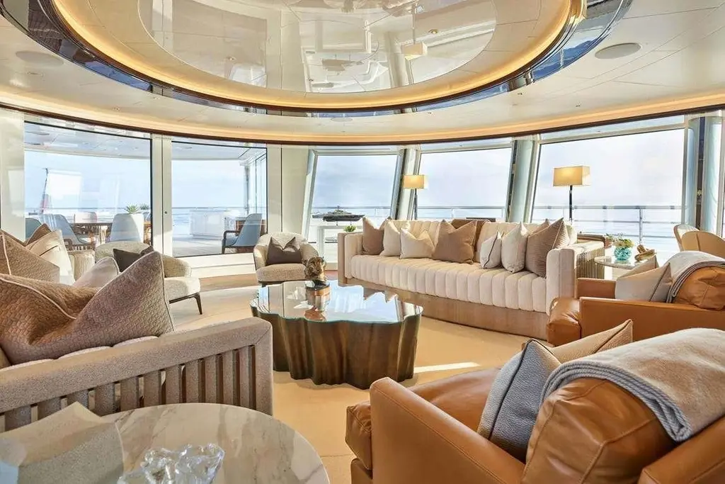 Curved lounge with full-height windows, a long cream sofa, leather armchairs and a sculpted coffee table