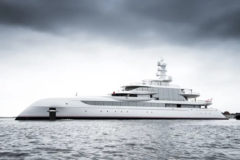 Excellence in full profile on grey water under a dark, cloudy sky