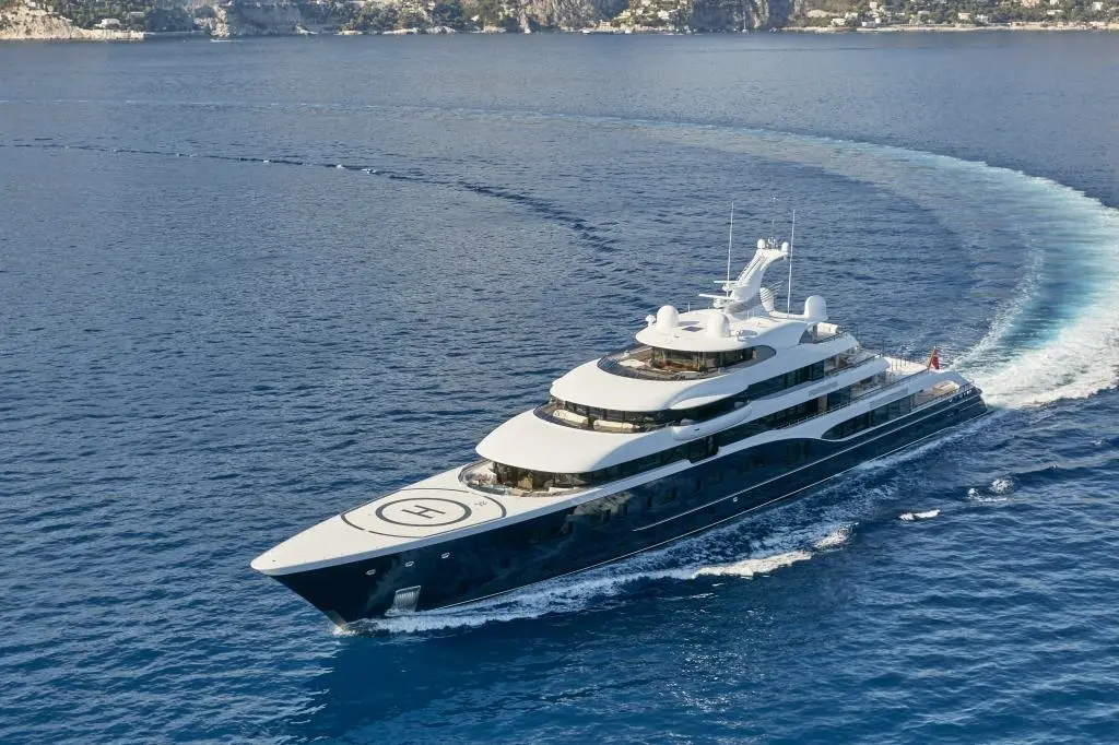 Aerial view of Symphony turning at sea, leaving a curved wake, helipad on the bow