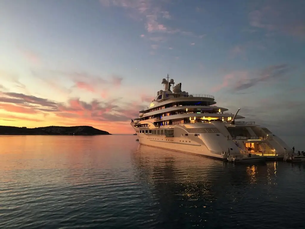 Dilbar's stern at sunset with the lit beach-club platform open at the waterline