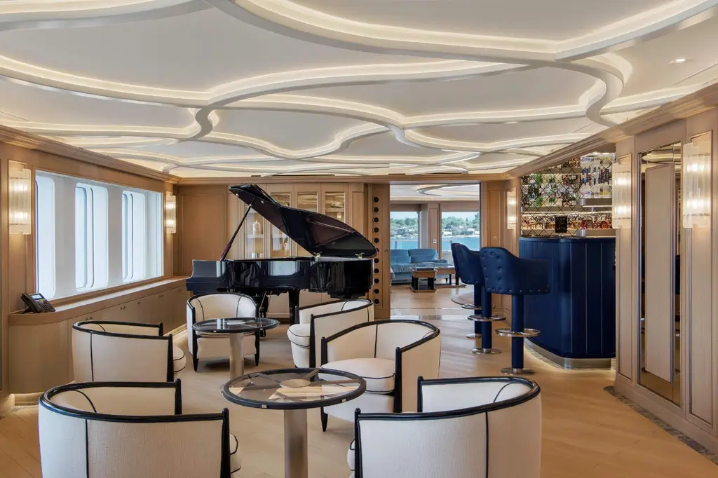 Lounge with a black grand piano, white armchairs and a blue bar, wave-patterned ceiling