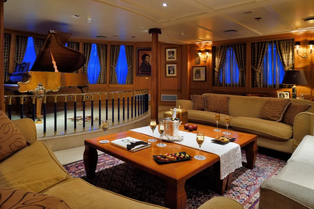 Wood-panelled lounge with sofas around a low table and a grand piano