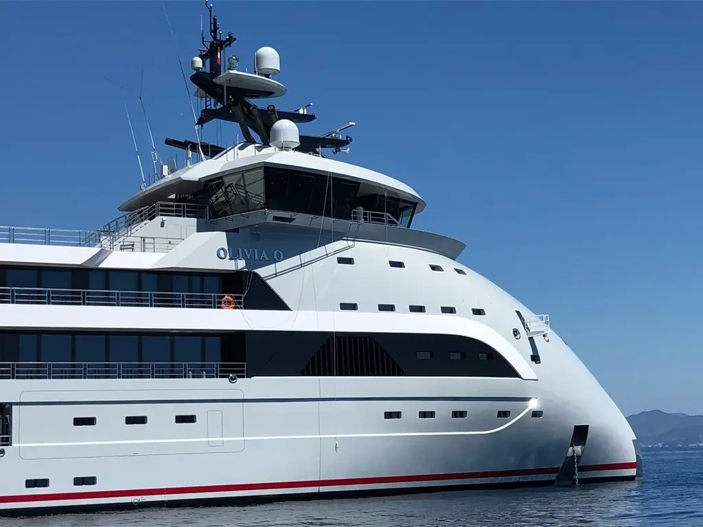 Close view of the forward superstructure of Olivia O: the wrap-around glass bridge, the mast with radar domes, and the yacht's name on the side