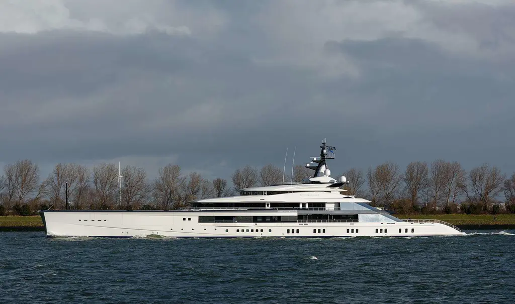 Bravo Eugenia passing along a river bank lined with bare trees under a grey sky