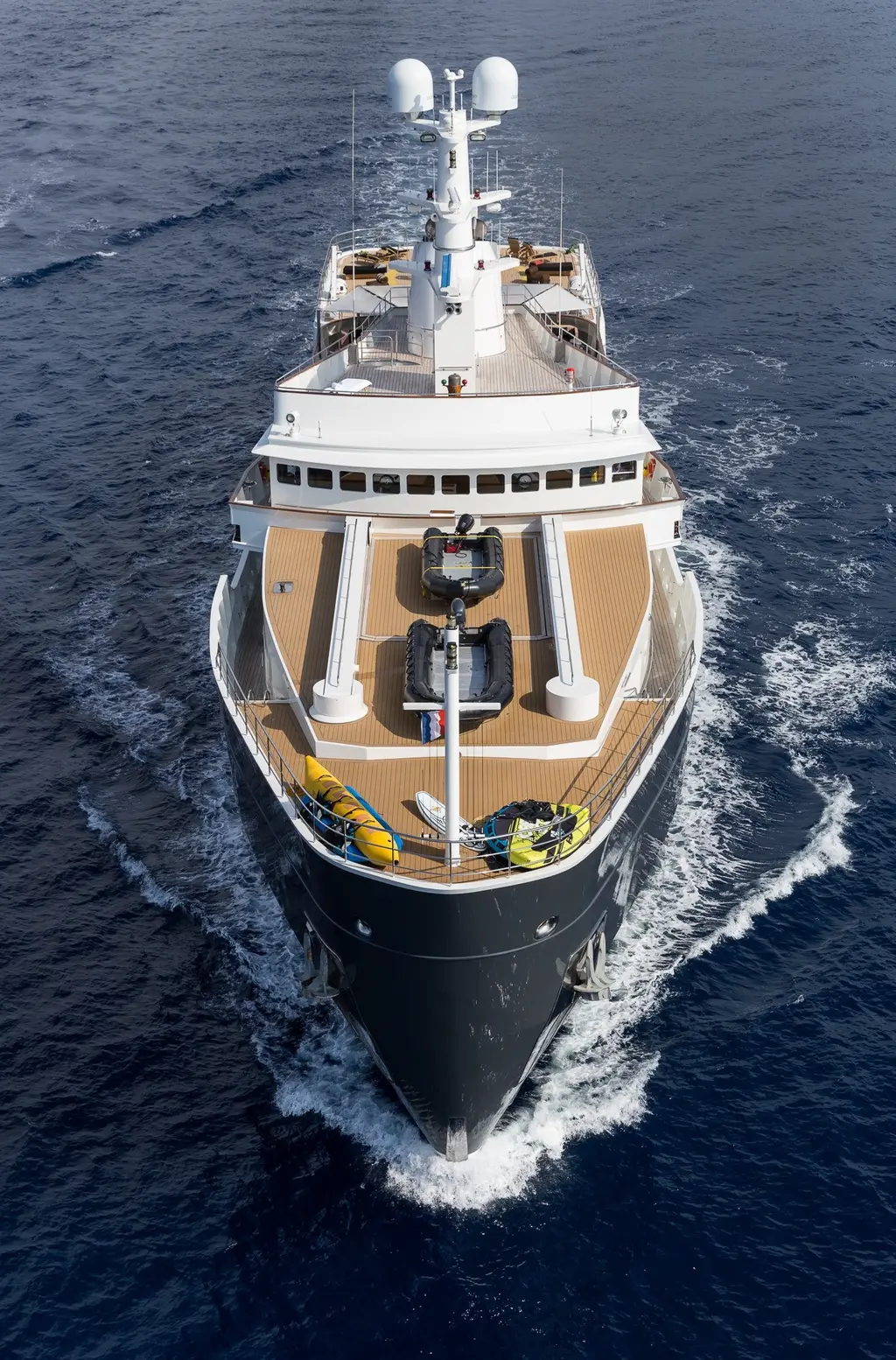 Aerial view of Legend from ahead, her high bow pushing a white bow wave and tenders stowed on the foredeck