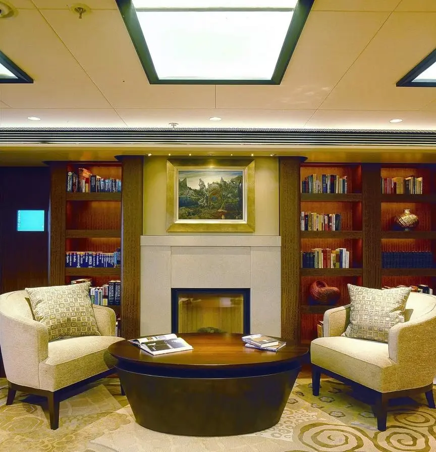 Library with bookshelves, a fireplace and two cream armchairs