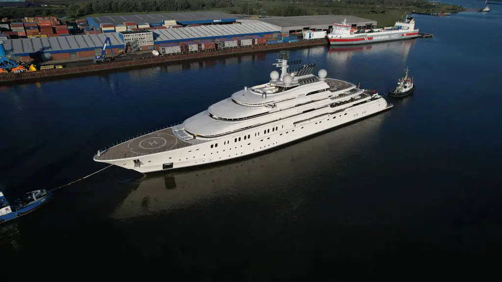 Aerial view of Opera from the bow under tow past a container quay